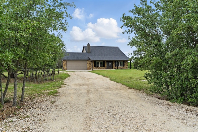 view of front of house with a front yard, a chimney, brick siding, dirt driveway, and an attached garage
