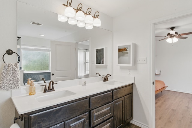 ensuite bathroom featuring double vanity, a sink, ensuite bathroom, and wood finished floors