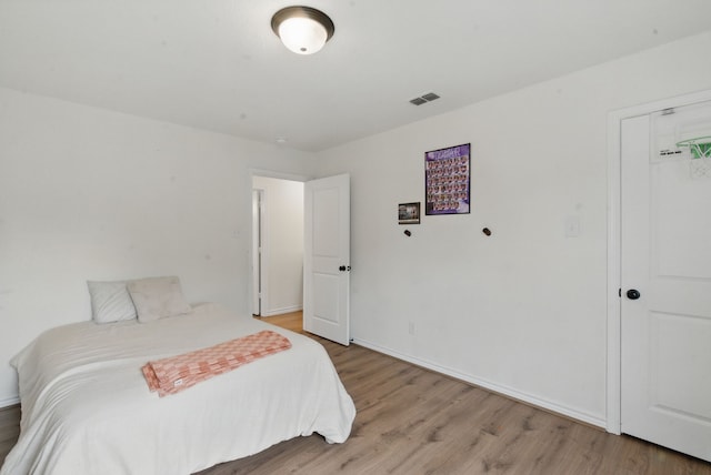 bedroom featuring baseboards, light wood-type flooring, and visible vents