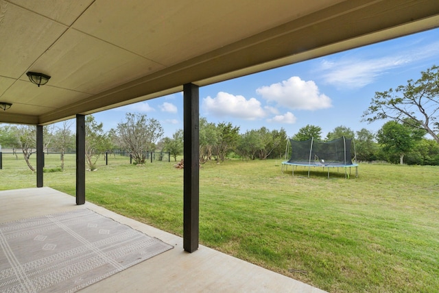 view of yard with fence, a trampoline, and a patio area