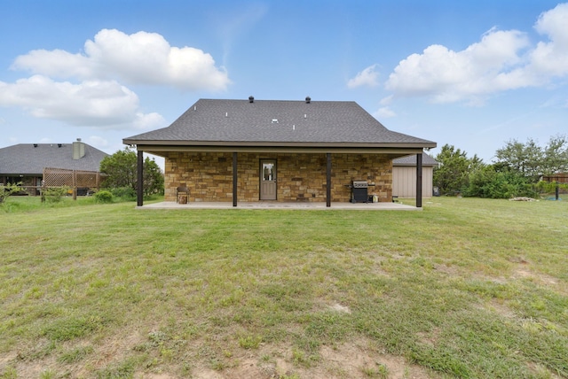back of property with a yard, a shingled roof, and a patio area