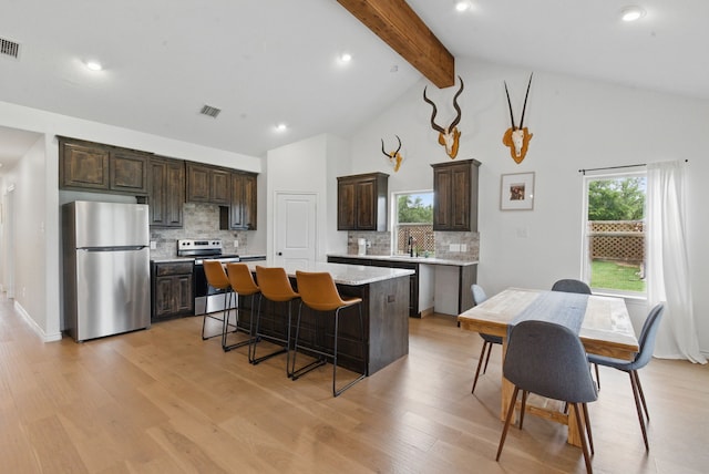 kitchen featuring dark brown cabinetry, a kitchen island, visible vents, beam ceiling, and stainless steel appliances