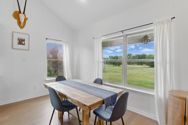 dining room featuring light wood-style floors, baseboards, and high vaulted ceiling