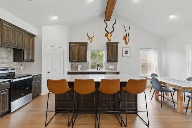 kitchen featuring a center island, a breakfast bar, dark brown cabinets, and stainless steel electric range oven