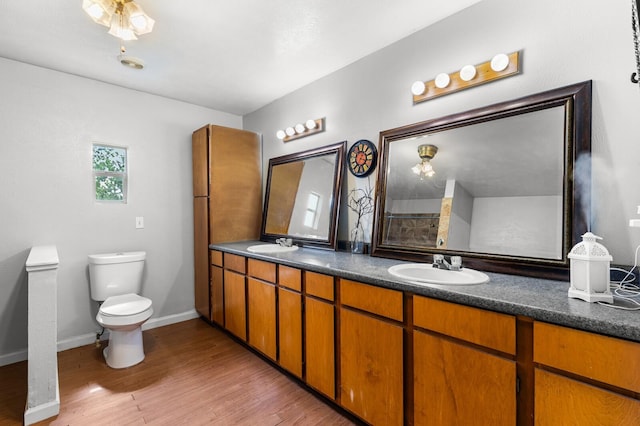 full bath with double vanity, a sink, wood finished floors, and toilet