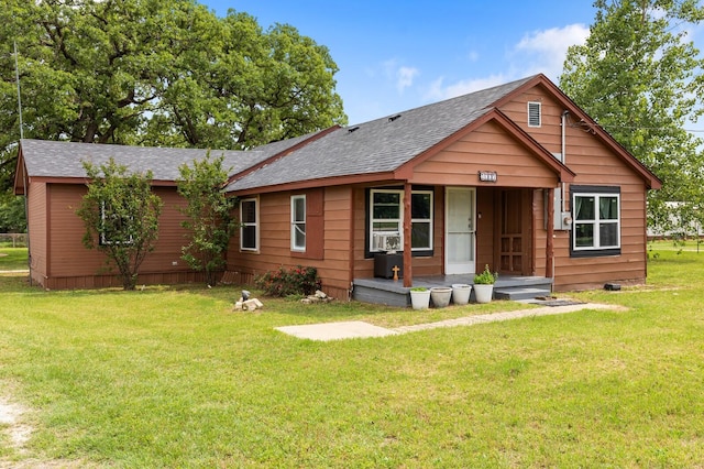 view of front facade with a shingled roof, covered porch, and a front yard