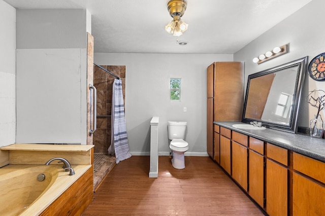full bath with a garden tub, a tile shower, wood finished floors, vanity, and toilet