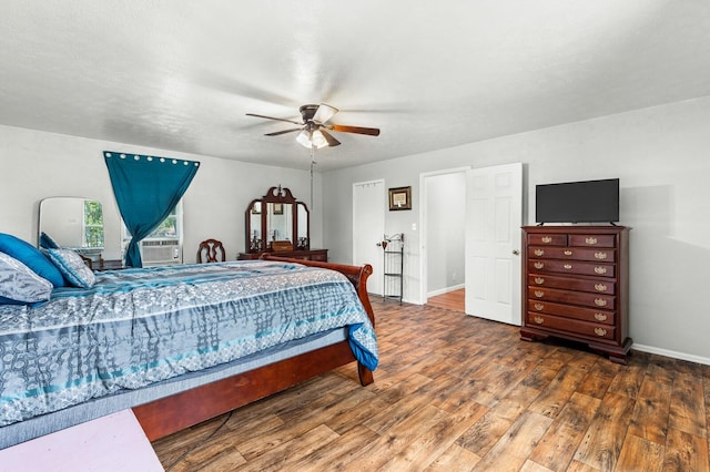 bedroom with baseboards, cooling unit, a ceiling fan, and wood finished floors