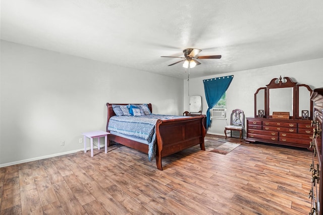 bedroom featuring baseboards, ceiling fan, wood finished floors, and cooling unit