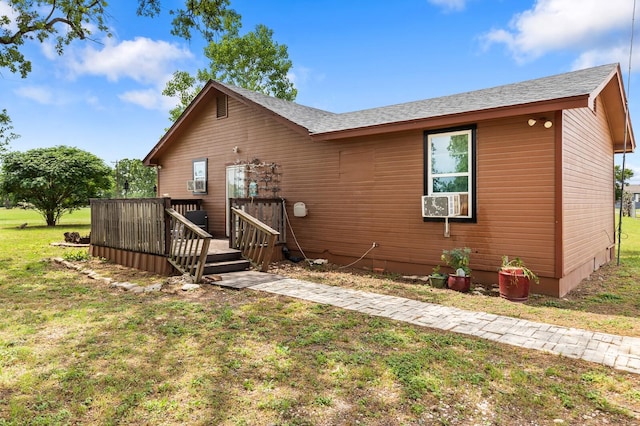 view of front of home featuring a shingled roof, a wooden deck, and a front yard