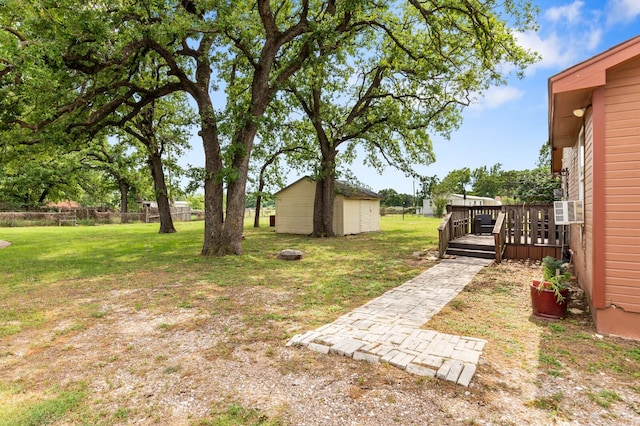 view of yard featuring fence, a shed, a deck, an outbuilding, and cooling unit