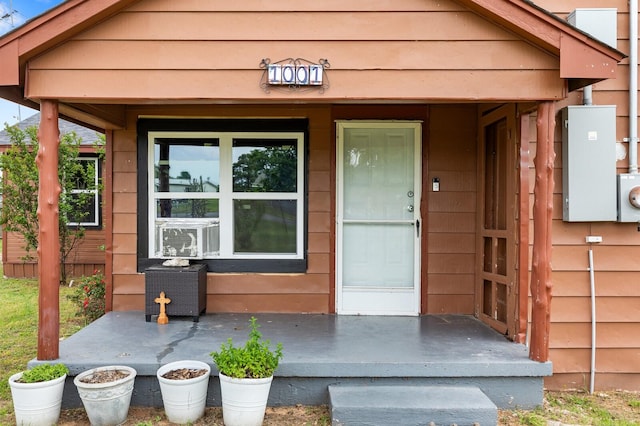 view of exterior entry featuring cooling unit and a porch