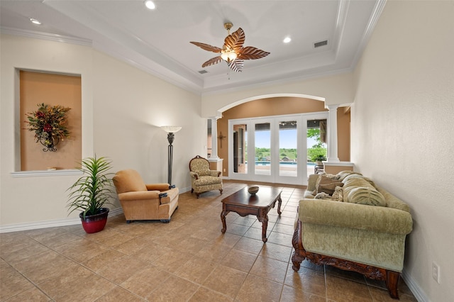 tiled living room featuring ornate columns, a ceiling fan, recessed lighting, arched walkways, and a tray ceiling