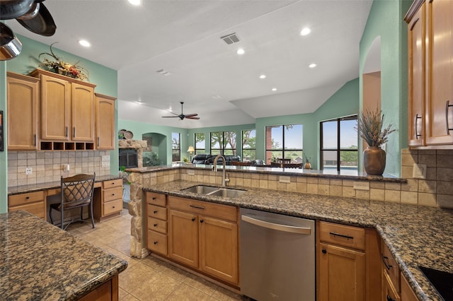 kitchen with stainless steel dishwasher, a sink, lofted ceiling, dark stone countertops, and backsplash