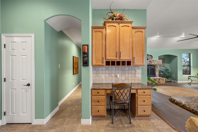office featuring light tile patterned floors, ceiling fan, baseboards, and a fireplace