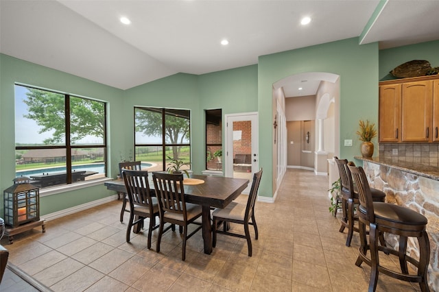 dining space with arched walkways, light tile patterned flooring, lofted ceiling, recessed lighting, and baseboards