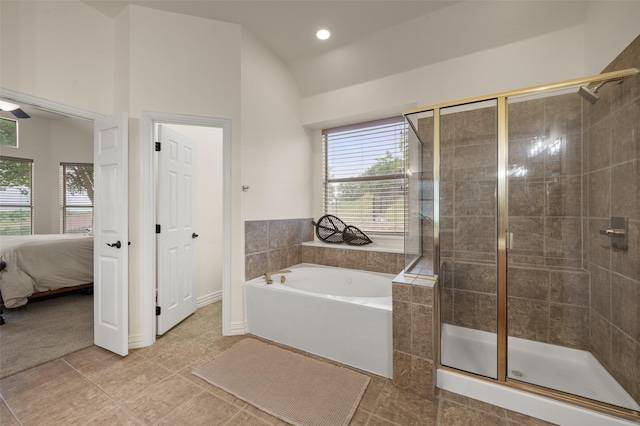 ensuite bathroom featuring healthy amount of natural light, a shower stall, tile patterned floors, vaulted ceiling, and a bath