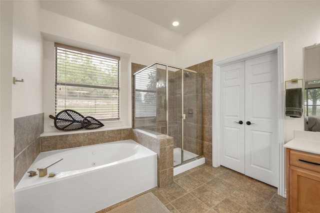 full bath featuring a shower stall, plenty of natural light, a garden tub, vanity, and lofted ceiling