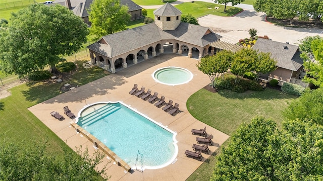 community pool with a yard, a hot tub, and a patio
