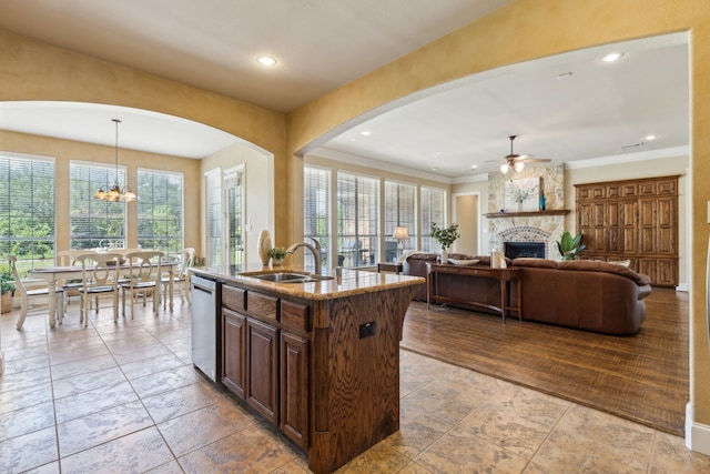5403 Englenook Dr, Parker, TX 75002 - kitchen featuring light stone countertops, a sink, arched walkways, a stone fireplace, and ceiling fan with notable chandelier