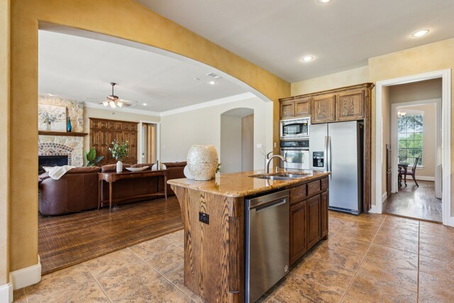 5403 Englenook Dr, Parker, TX 75002 - kitchen with appliances with stainless steel finishes, light stone counters, a sink, arched walkways, and an island with sink
