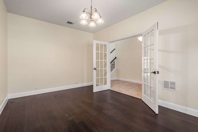 spare room with a notable chandelier, visible vents, french doors, and wood finished floors