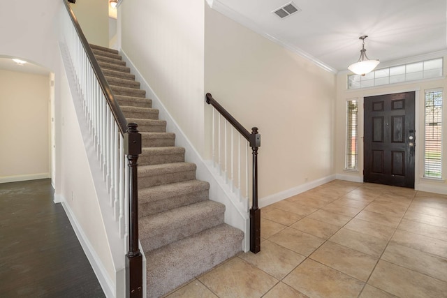 foyer featuring crown molding, baseboards, visible vents, and stairway