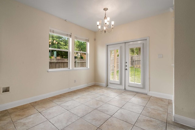 empty room featuring french doors, light tile patterned floors, a notable chandelier, and a wealth of natural light