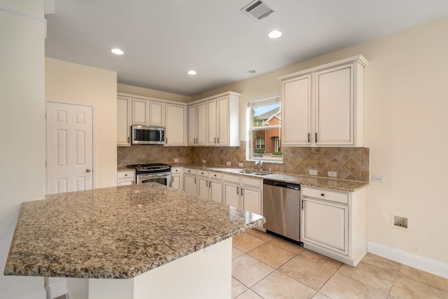 kitchen featuring backsplash, visible vents, a sink, light stone counters, and stainless steel appliances
