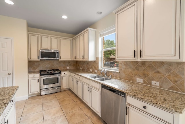 kitchen featuring appliances with stainless steel finishes, a sink, recessed lighting, decorative backsplash, and cream cabinetry