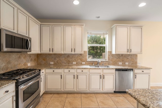 kitchen featuring a sink, appliances with stainless steel finishes, tasteful backsplash, and light tile patterned floors