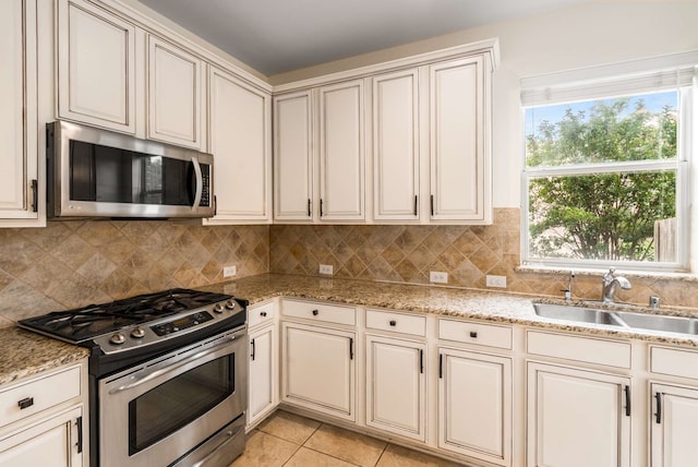 kitchen featuring a sink, decorative backsplash, appliances with stainless steel finishes, and light tile patterned flooring