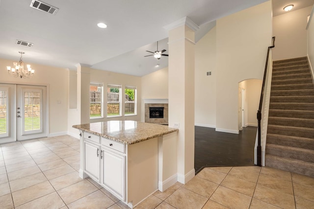 kitchen featuring visible vents, light stone countertops, baseboards, ceiling fan with notable chandelier, and light tile patterned flooring