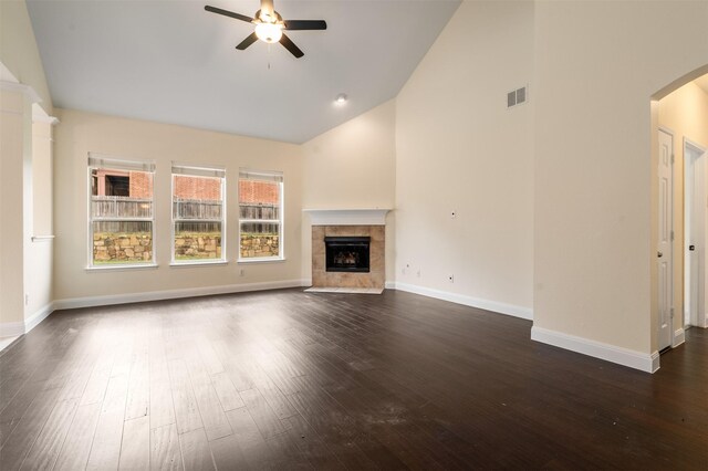2719 Foxpoint Trl, Arlington, TX 76017 - unfurnished living room with ceiling fan, arched walkways, dark wood-type flooring, a tiled fireplace, and high vaulted ceiling