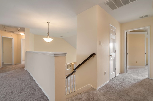 corridor featuring visible vents, attic access, carpet, and an upstairs landing