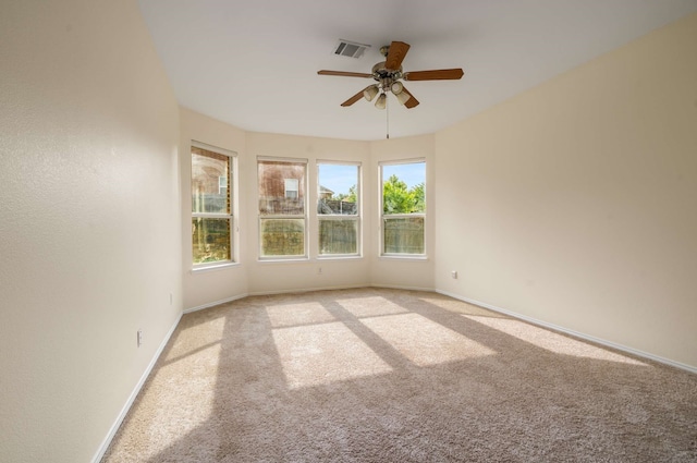 unfurnished room with ceiling fan, visible vents, light carpet, and baseboards