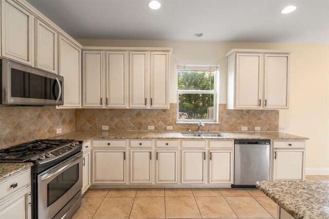 2719 Foxpoint Trl, Arlington, TX 76017 - kitchen with appliances with stainless steel finishes, a sink, cream cabinets, recessed lighting, and backsplash