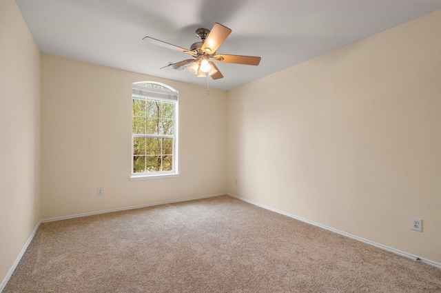 carpeted spare room featuring baseboards and ceiling fan