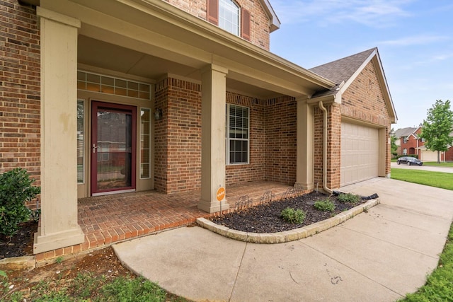 entrance to property featuring an attached garage, driveway, and brick siding