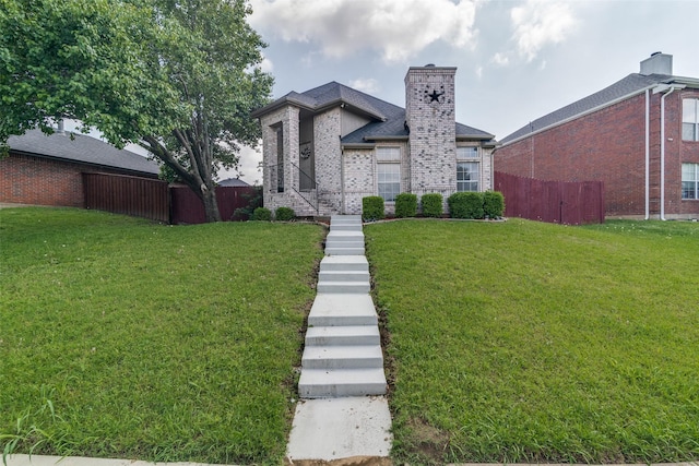 view of front of house with brick siding, fence, a front yard, and a chimney