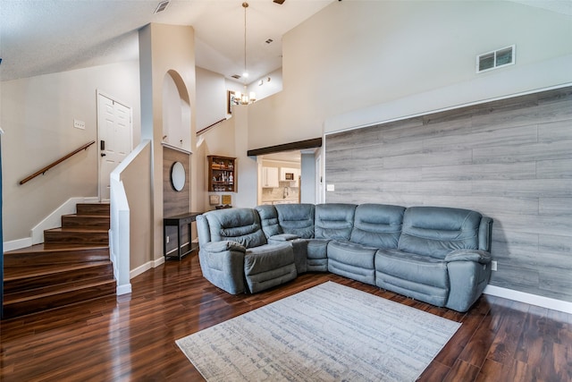 living room with an inviting chandelier, high vaulted ceiling, baseboards, wood finished floors, and visible vents