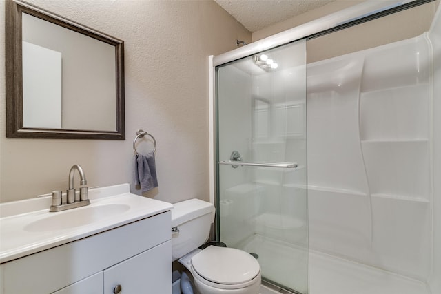 bathroom featuring a textured ceiling, a shower stall, vanity, toilet, and a textured wall