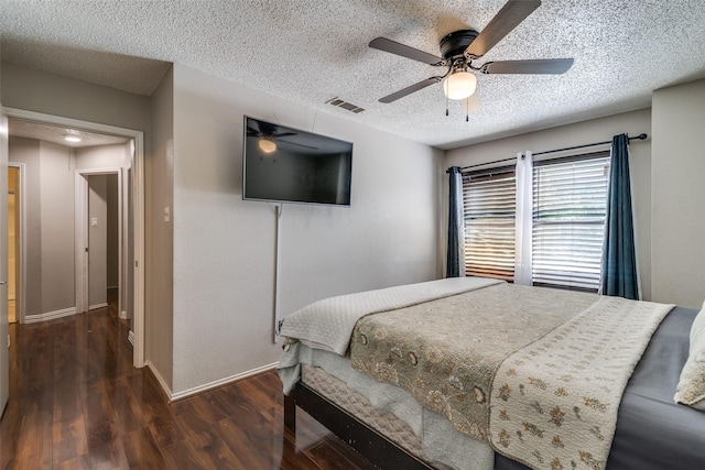 bedroom featuring a ceiling fan, a textured ceiling, visible vents, wood finished floors, and baseboards