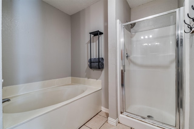 bathroom with a bath, tile patterned floors, a shower stall, and a textured ceiling