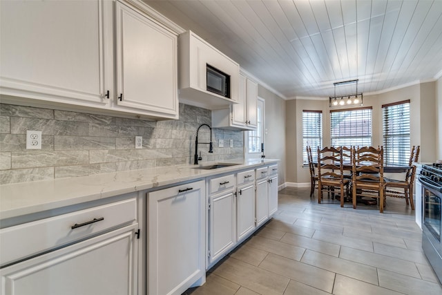 kitchen featuring crown molding, a sink, white cabinetry, and backsplash