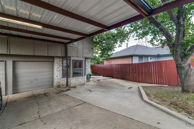 view of patio with a garage, fence, and driveway