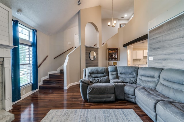 living area featuring an inviting chandelier, baseboards, wood finished floors, visible vents, and stairway