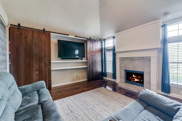 living area with a textured ceiling, plenty of natural light, baseboards, wood finished floors, and a tile fireplace