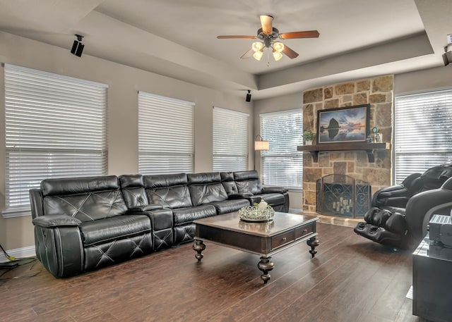 living area with a raised ceiling, ceiling fan, wood finished floors, and a healthy amount of sunlight