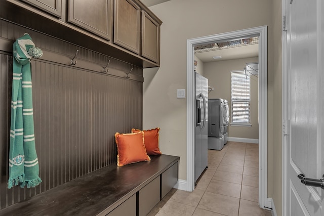 mudroom featuring baseboards, light tile patterned floors, and washing machine and dryer